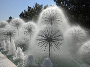 A whimsical dandelion fountain, designed by RES Group, featuring unique water bursts in a natural setting