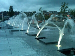 An interactive fountain with curved jets, designed by RES Group, engaging visitors with dynamic water play