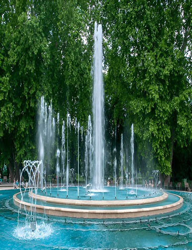 A vibrant fountain display in a lush, green park, showcasing multiple water jets rising gracefully from a circular pool. This image highlights the expertise of RES Group in fountain design, blending aesthetic appeal with innovative water features, perfect for transforming outdoor spaces into luxurious retreats or community highlights.
