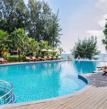 A stunning infinity pool surrounded by lush tropical greenery and wooden deck chairs, reflecting RES Group's expertise in swimming pool construction. The serene water feature and luxurious outdoor setting exemplify the company's ability to create sustainable and aesthetically pleasing lifestyle solutions for modern residential or commercial spaces.