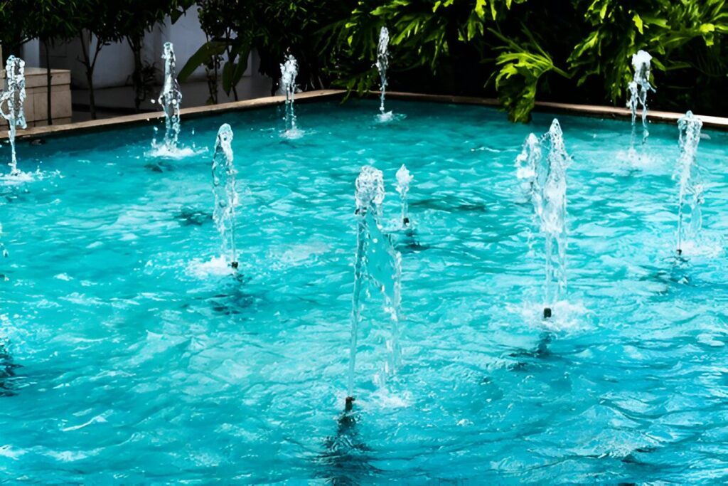 Multiple white water jets erupting before modern glass building