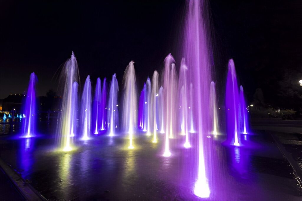 Illuminated purple and white jets dancing in nighttime square